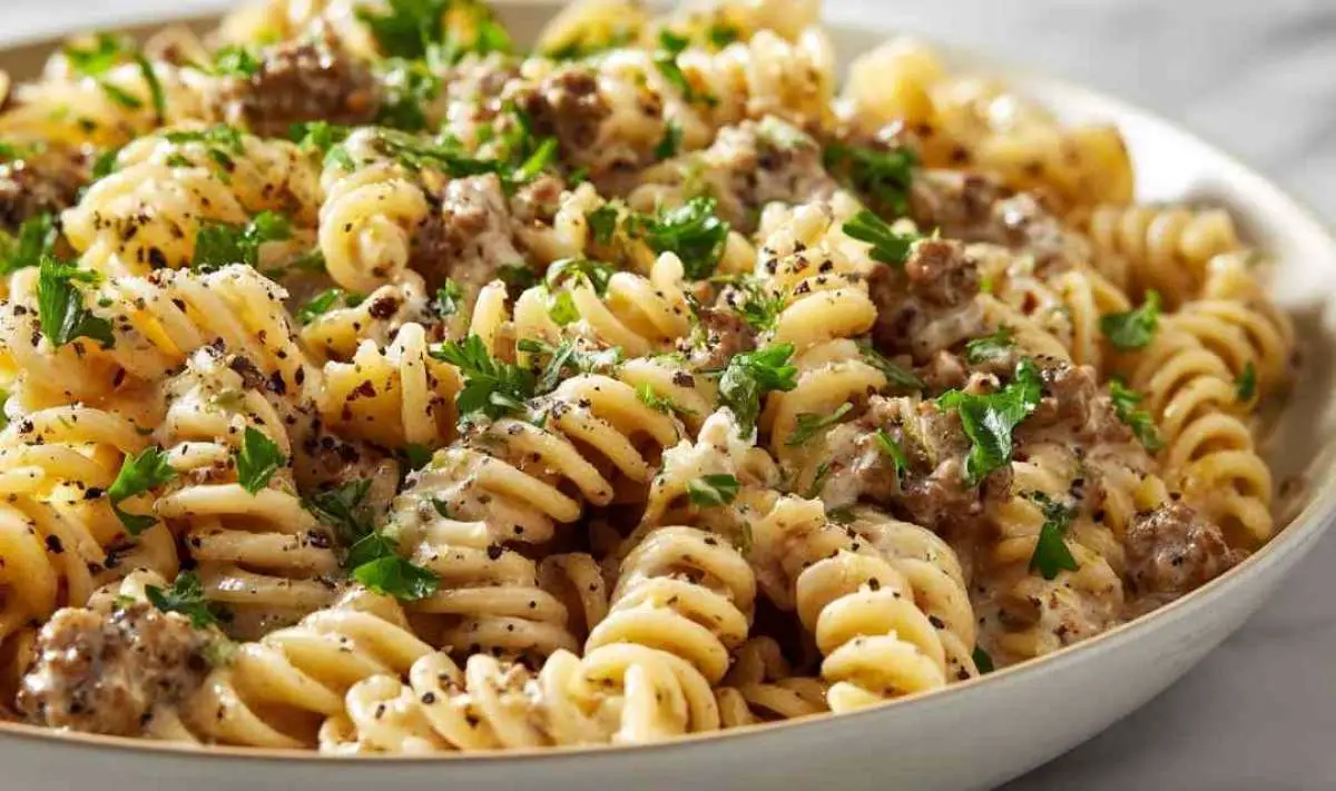 Beef and rotini in garlic parmesan sauce served in white bowl with fresh parsley garnish