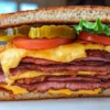 Fried bologna sandwich meal with potato chips and pickle spears