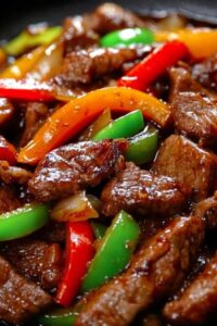 Sizzling pepper steak with onions served over rice garnished with green onions
