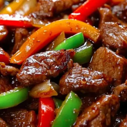Sizzling pepper steak with onions served over rice garnished with green onions