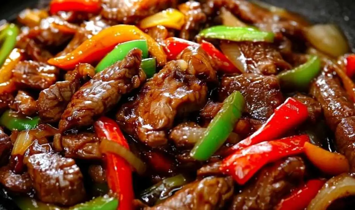 Cooking pepper steak with bell peppers and onions in a hot wok