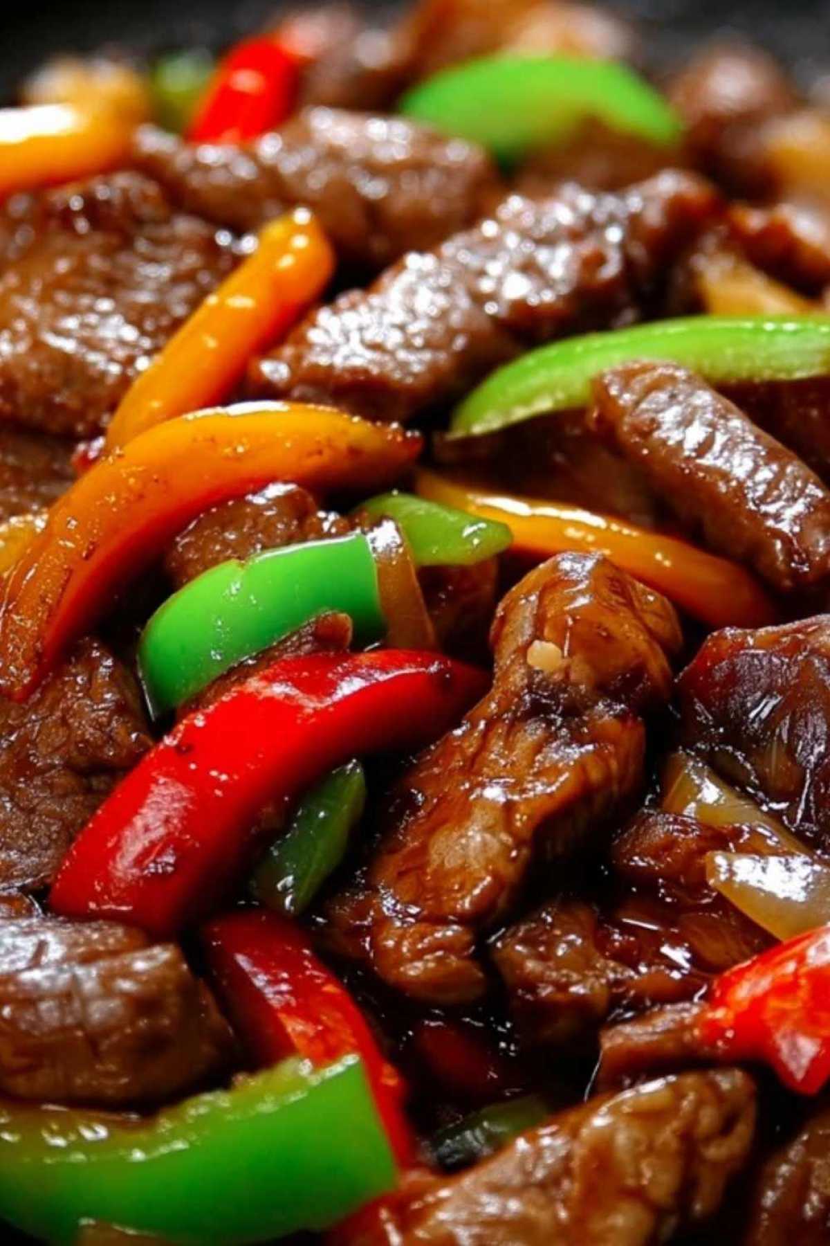 Fresh ingredients for pepper steak including sliced beef, bell peppers, and onions