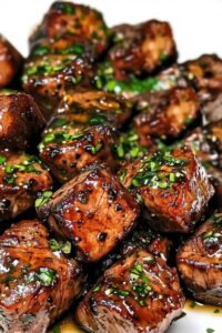 Finished steak bites with stew meat garnished with fresh herbs on serving platter