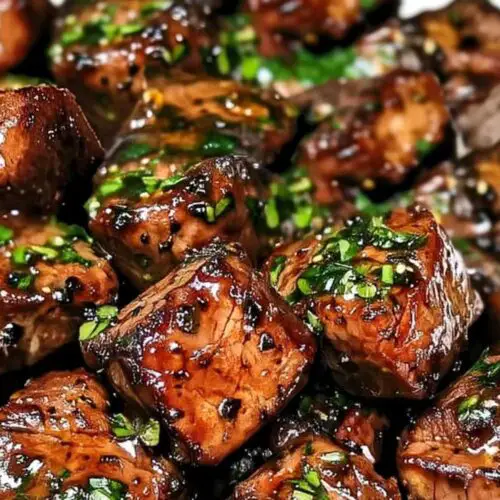 Finished steak bites with stew meat garnished with fresh herbs on serving platter