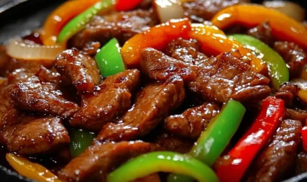 Fresh ingredients for pepper steak including sliced beef, bell peppers, and onions