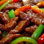 Fresh ingredients for pepper steak including sliced beef, bell peppers, and onions