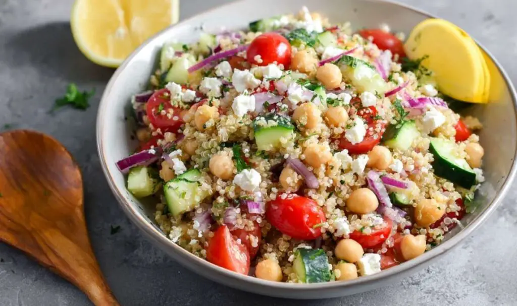Greek quinoa salad ingredients laid out including quinoa, vegetables, feta, and lemon dressing components