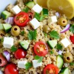 Mixing Greek Quinoa Salad with wooden spoon showing texture and colors