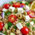 Mixing Greek Quinoa Salad with wooden spoon showing texture and colors