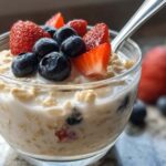 High protein overnight oats topped with fresh berries in a mason jar