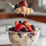 High protein overnight oats topped with fresh berries in a mason jar