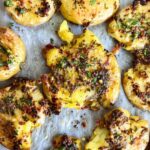 Plated lemon herb smashed potatoes with fresh herbs and lemon zest garnish