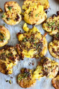 Plated lemon herb smashed potatoes with fresh herbs and lemon zest garnish