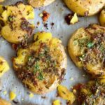 Plated lemon herb smashed potatoes with fresh herbs and lemon zest garnish