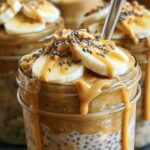 Glass jars of peanut butter banana overnight oats with banana slices on top ready for refrigerator