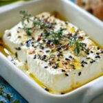 Golden Albanian baked feta with honey drizzled on top and sesame seeds, served with crusty bread
