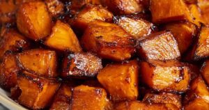Finished honey roasted sweet potatoes with crispy caramelized edges served in white bowl