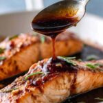 Honey glazed salmon fillet on white plate with caramelized golden edges