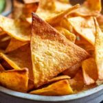 Golden brown easy keto tortilla chips arranged on white plate with guacamole dip