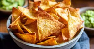 Golden brown easy keto tortilla chips arranged on white plate with guacamole dip