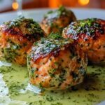 Salmon balls with creamy avocado sauce served on white plate with fresh herbs