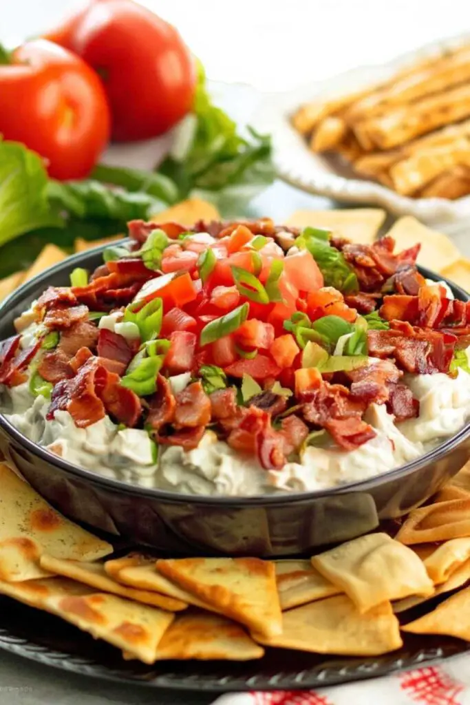 Creamy BLT dip topped with crispy bacon, diced tomatoes, and fresh lettuce in white serving bowl