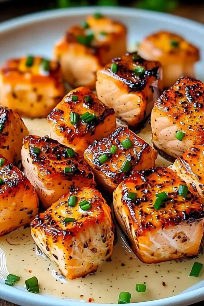 Bang Bang Salmon Bites served on white plate with green onions and sesame seeds
