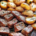 Butter steak bites with garlic herb potatoes served on white plate with fresh herbs