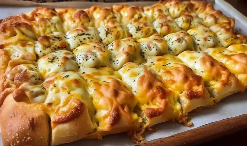 Rolling pizza dough for cheesy garlic breadsticks with garlic butter being brushed on top