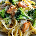 Plated creamy chicken and broccoli pasta with extra Parmesan cheese and fresh herbs