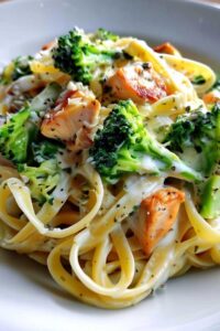 Plated creamy chicken and broccoli pasta with extra Parmesan cheese and fresh herbs