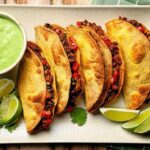 Crispy black bean tacos served with avocado slices and salsa verde