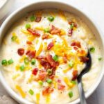 Easy baked potato soup in white bowl topped with bacon cheese and scallions