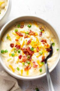 Easy baked potato soup in white bowl topped with bacon cheese and scallions