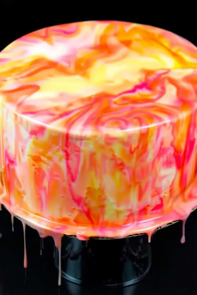Pouring colorful easy mirror glaze recipe over chilled buttercream cake