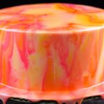 Pouring colorful easy mirror glaze recipe over chilled buttercream cake
