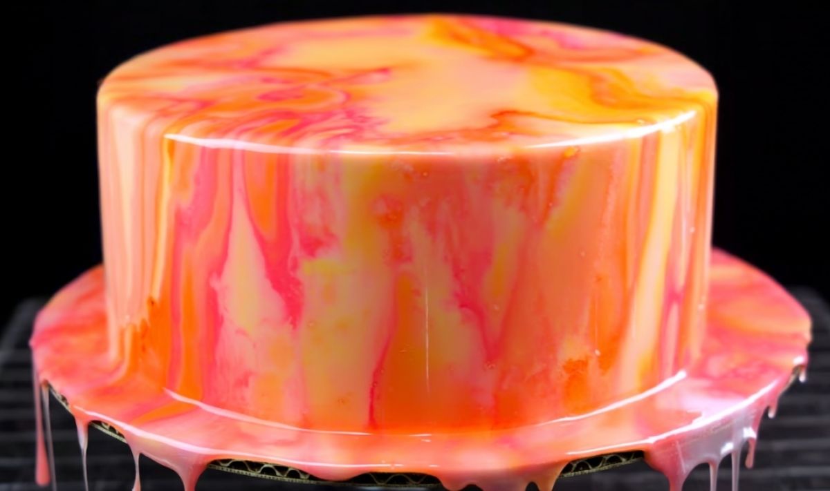 Pouring colorful easy mirror glaze recipe over chilled buttercream cake