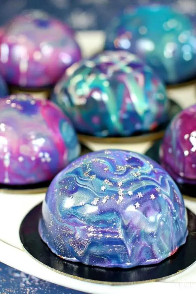 Beautiful Galaxy Mousse Cakes with cosmic mirror glaze swirls on white plates