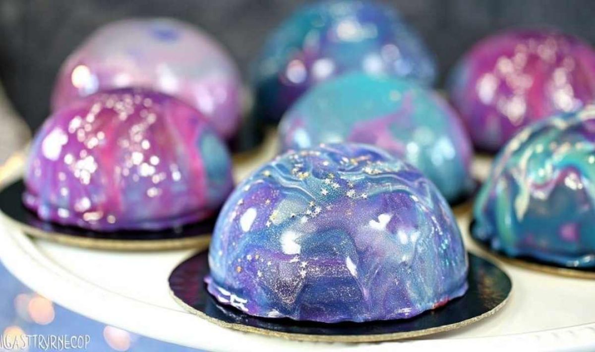 Pouring colorful mirror glaze over Galaxy Mousse Cakes creating cosmic effect