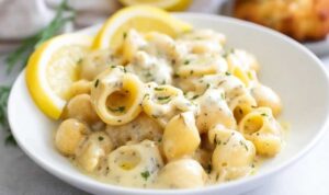 Creamy garlic butter pasta in white bowl with fresh herbs and Parmesan cheese