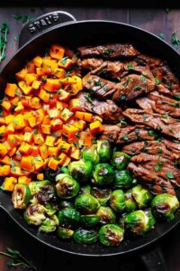 Garlic butter steak with Brussels sprouts and butternut squash served on white plate