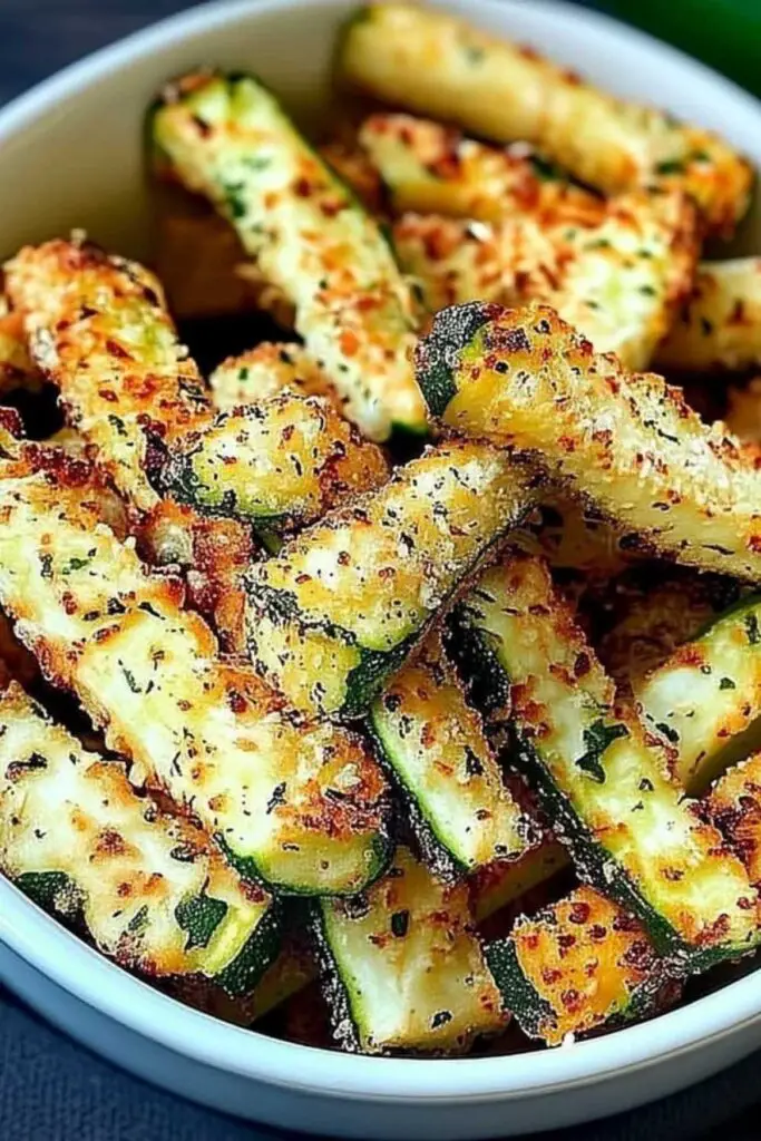 Breaded zucchini fries arranged in air fryer basket before cooking