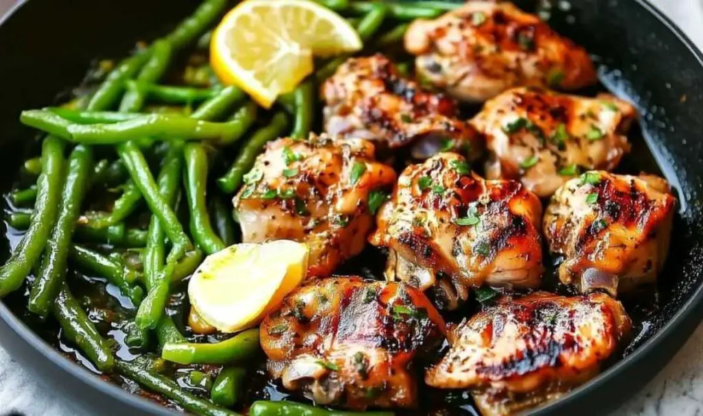 Lemon garlic butter chicken green beans skillet served on white plate with lemon wedges