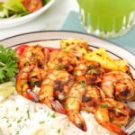 Marinated grilled shrimp served over rice with grilled pineapple and bell peppers