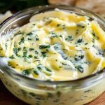 Rich and creamy garlic butter melting in saucepan with fresh herbs