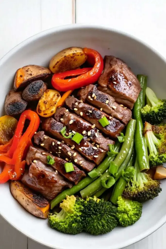 Sheet pan beef and broccoli with colorful vegetables on parchment-lined baking sheet
