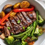 Raw marinated beef and fresh vegetables arranged on sheet pan before roasting