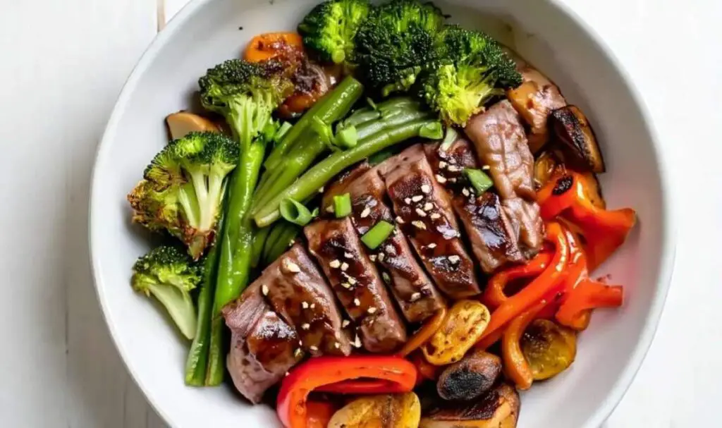 Plated sheet pan beef and broccoli served over jasmine rice with green onion garnish