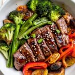 Plated sheet pan beef and broccoli served over jasmine rice with green onion garnish