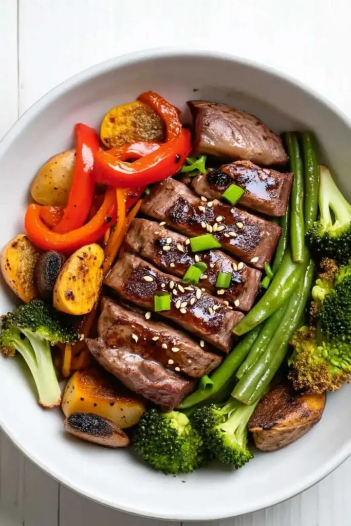Plated sheet pan beef and broccoli served over jasmine rice with green onion garnish
